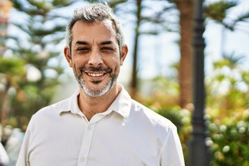 Middle age grey-haired man smiling happy standing at the city.