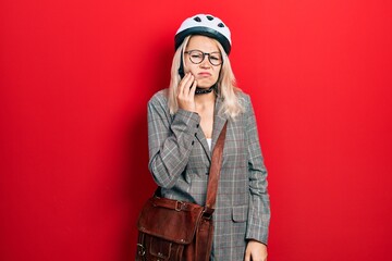 Beautiful caucasian blonde business woman wearing bike helmet touching mouth with hand with painful expression because of toothache or dental illness on teeth. dentist