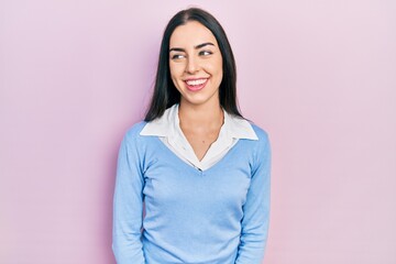 Fototapeta premium Beautiful woman with blue eyes standing over pink background looking away to side with smile on face, natural expression. laughing confident.