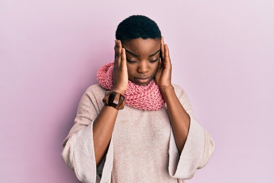 Young african american woman wearing winter scarf suffering from headache desperate and stressed because pain and migraine. hands on head.