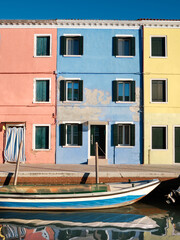Fototapeta na wymiar Colorful houses by canal in Burano island, Italy. Historic italian architecture in historic village not far from Venice.