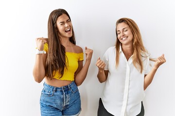 Mother and daughter together standing together over isolated background celebrating surprised and amazed for success with arms raised and eyes closed. winner concept.