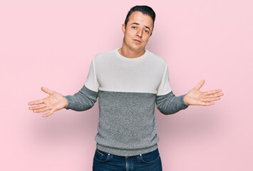 Handsome young man wearing casual winter sweater clueless and confused expression with arms and...
