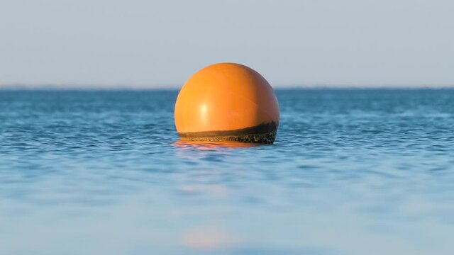 Yellow buoy floating on sea surface as marker for swimming restriction in deep water at tropical resort. Human life safety concept