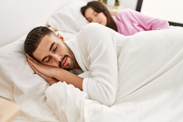 Young hispanic couple sleeping on bed at home.