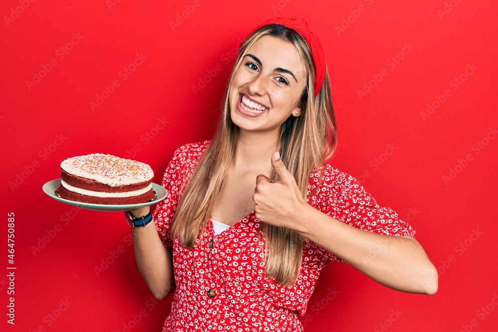 Canvas Prints Beautiful hispanic woman holding strawberry cake smiling happy and positive, thumb up doing excellent and approval sign