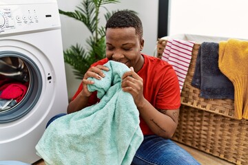 Young african man smelling fresh towel at laundry room