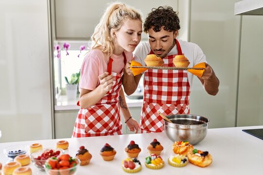 Young couple smiling happy cooking sweets at kitchen.