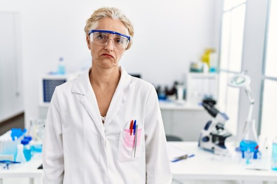 Middle age blonde woman working at scientist laboratory depressed and worry for distress, crying angry and afraid. sad expression.