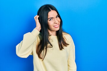 Young brunette woman wearing casual sweatshirt confuse and wonder about question. uncertain with...