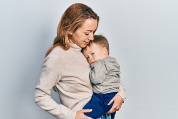 Young caucasian woman holding and hugging her son with love. Family of two bonding together. Mother holding infant toddler