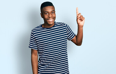 Young african american man wearing casual striped t shirt smiling with an idea or question pointing finger up with happy face, number one © Krakenimages.com