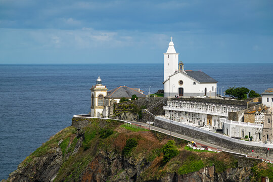 Picturesque chapel with cementery and a lighthouse overlooking Cantabrian sea in the village of Luarca, Asturias, Spain.