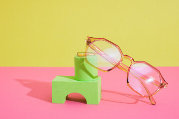 trendy eye glasses on geometric pink podiums, colorful background, copy space