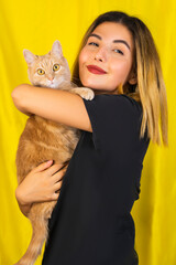 Beautiful girl is holding up in arms a red cat