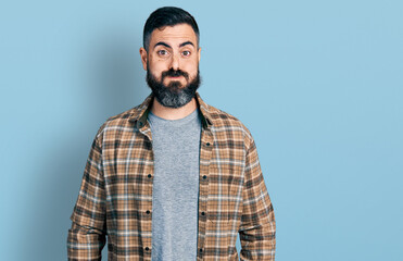 Hispanic man with beard wearing casual shirt puffing cheeks with funny face. mouth inflated with air, crazy expression.