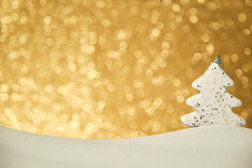 white christmas tree figure on white surface and shiny golden background