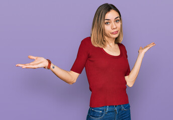 Young blonde girl wearing casual clothes clueless and confused expression with arms and hands...