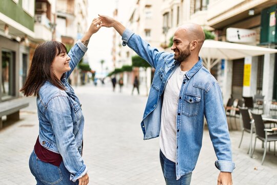 Young hispanic couple smiling happy dancing at the city.