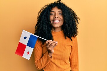 African american woman with afro hair holding panama flag looking positive and happy standing and smiling with a confident smile showing teeth