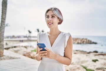 Young caucasian girl smiling happy using smartphone at the beach.