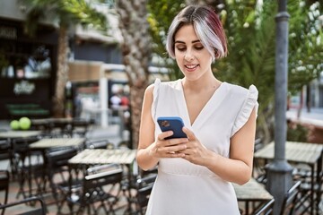 Young caucasian girl smiling happy using smartphone at the city.