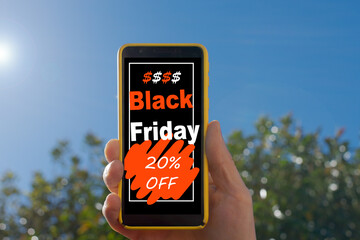 Hand holding a smartphone that on the screen advertises 20% discount for black friday