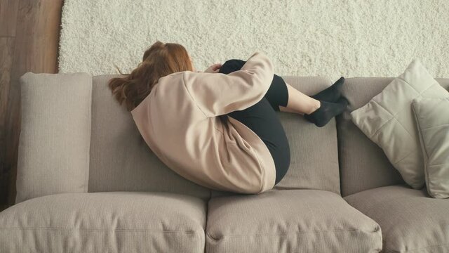 View From Above. A Pensive Red-haired Girl is Sad Alone at Home. A Depressed Teenager Suffers From Loneliness, Lack of Communication, Lack of Friends. Mental Health.