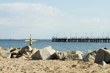 Kamienisty falochron na plaży w tle mechanizm do wyciągania kutrów i drewniane molo