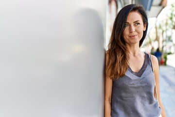 Fototapeta premium Beautiful caucasian woman looking elegant and happy leaning on a wall outdoors on a sunny day