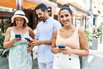 Obraz premium Three hispanic friends smiling happy using smartphone at the city.
