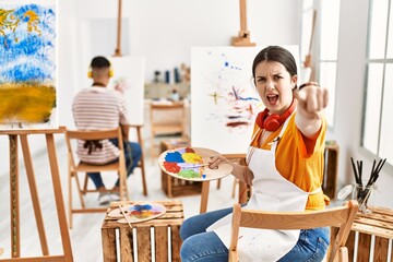 Young artist woman painting on canvas at art studio pointing displeased and frustrated to the camera, angry and furious with you © Krakenimages.com