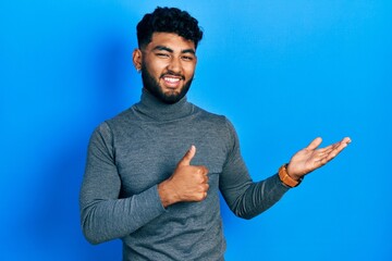 Arab man with beard wearing turtleneck sweater showing palm hand and doing ok gesture with thumbs...