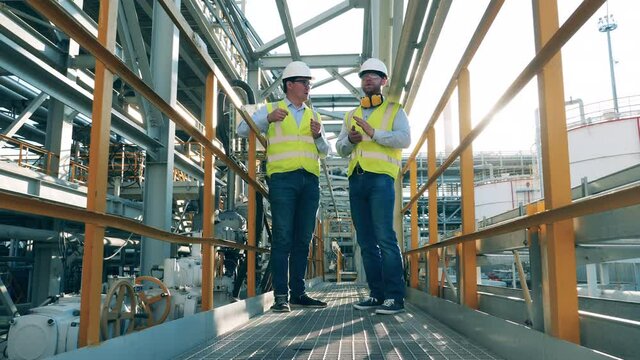 Male co-workers are discussing petroleum refinery constructions
