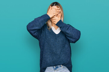 Young caucasian woman wearing casual clothes covering eyes and mouth with hands, surprised and shocked. hiding emotion