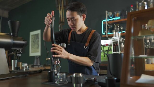 Asian man barista making hot espresso shot from flair espresso coffee maker at cafe. Male coffee shop owner brewing black coffee serving to customer. Small business restaurant food and drink concept