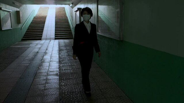 無人の地下通路を歩く女性に近づく不審者
