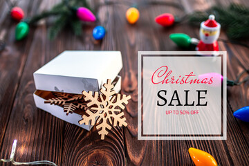 Gift box with hand-carved wooden snowflakes. Text Christmas sale. up to 50 off , Christmas sale, discounts template with christmas decorations, garland with colorful light bulbs