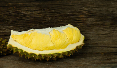 A Durian with golden ripe meat on wooden background. Durian is the king of fruit and the most famous fruit in Thailand. Copy space for text.
