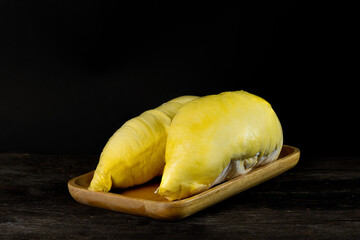 Durian with two golden ripe meat on the wooden tray with a dark and wooden floor background. Durian is the king of fruit and the most famous of fruit from Thailand.