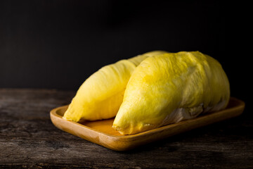 Durian with two golden ripe meat on the wooden tray with a dark and wooden floor background. Durian is the king of fruit and the most famous of fruit from Thailand.