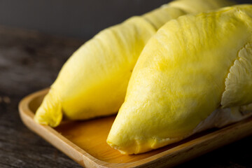 Close up Durian with golden ripe meat on the wooden tray with a dark wooden background. Durian is the king of fruit and the most famous fruit in Thailand.