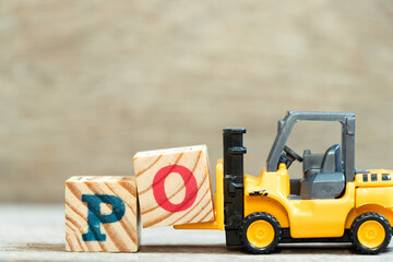 Toy forklift hold letter block o to complete word PO (Abbreviation of purchase order) on wood background