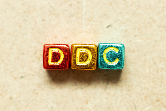 Metallic Color Alphabet Letter Block In Word DDC (Abbreviation Of Division Of Disease Control,  Direct Digital Control, Display Data Channel Or Dewey Decimal Classification) On Wood Background