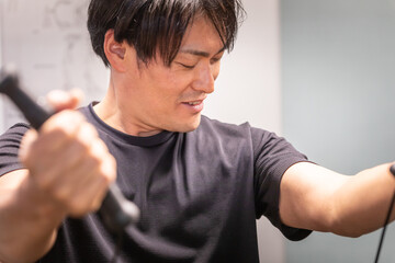スポーツジムでケーブルマシンを使う男性
