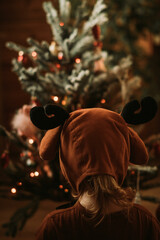 Toddler baby girl in rudolph reindeer costumes decorating Christmas tree