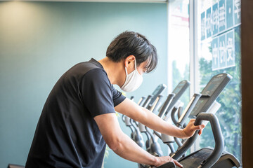 エアロバイクで運動する男性（マスク）
