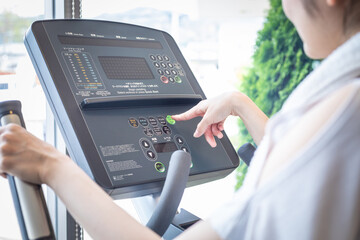 ウォーキングマシンのパネルを操作する女性
