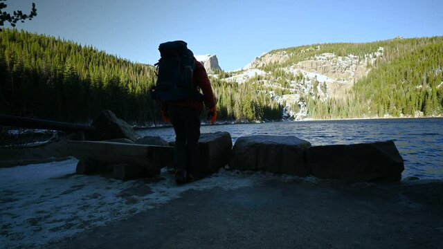 Hiker relaxes on a bench at one of the most popular alpine lakes in Rocky Mountain National Park, Bear Lake, Estes Park, Colorado
