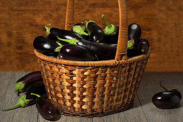 Eggplant in a wicker basket on a wooden background